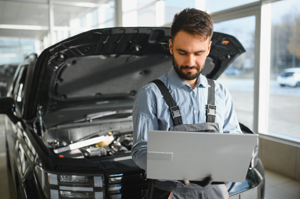 Automotive mechanic running diagnostics software on computer. Mechanic doing vehicle diagnostic test in auto service garage